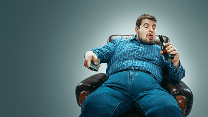 Image showing Fat man sitting in a brown armchair, emotional watching TV