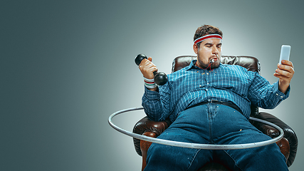 Image showing Fat man sitting in a brown armchair, emotional watching TV