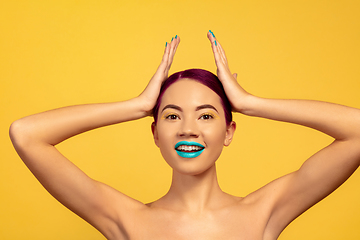 Image showing Portrait of beautiful young woman with bright make-up isolated on yellow studio background