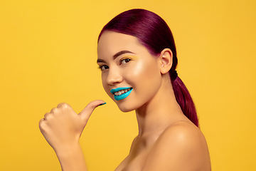 Image showing Portrait of beautiful young woman with bright make-up isolated on yellow studio background