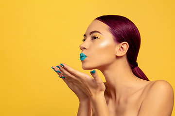 Image showing Portrait of beautiful young woman with bright make-up isolated on yellow studio background