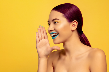 Image showing Portrait of beautiful young woman with bright make-up isolated on yellow studio background