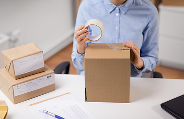 Image showing woman packing parcel box with adhesive tape