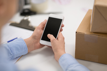 Image showing hands with smartphone and parcels at post office