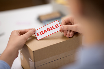 Image showing woman sticking fragile mark to parcel box