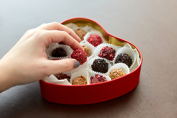 Image showing hand with candies in heart shaped chocolate box