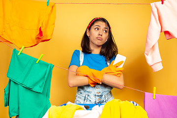 Image showing Funny and beautiful housewife doing housework on yellow background