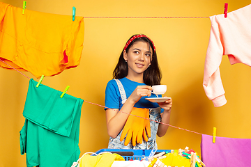 Image showing Funny and beautiful housewife doing housework on yellow background