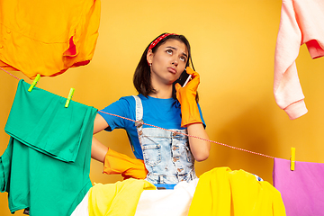 Image showing Funny and beautiful housewife doing housework on yellow background