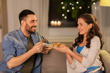 Image showing happy couple drinking tea with cookies at home