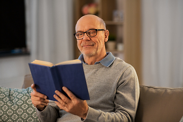 Image showing happy bald senior man on sofa reading book at home
