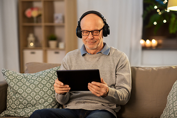 Image showing senior man with tablet pc and headphones at home