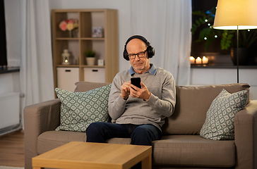 Image showing senior man with smartphone and headphones at home