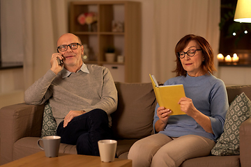 Image showing senior couple with book and smartphone at home