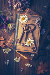 Image showing Key to knowledge concept. Old keys on a vintage book with flowers on wooden background