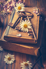 Image showing Key to knowledge concept. Old keys on a vintage book with flowers on wooden background