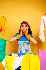 Image showing Funny and beautiful housewife doing housework on yellow background