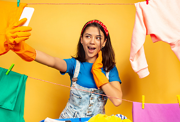 Image showing Funny and beautiful housewife doing housework on yellow background