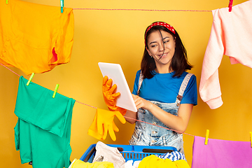 Image showing Funny and beautiful housewife doing housework on yellow background