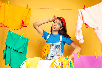 Image showing Funny and beautiful housewife doing housework on yellow background