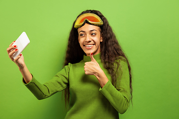 Image showing African-american young woman\'s portrait in ski mask on green background