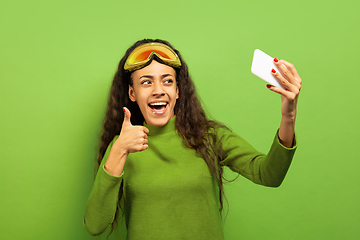 Image showing African-american young woman\'s portrait in ski mask on green background