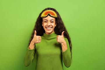 Image showing African-american young woman\'s portrait in ski mask on green background