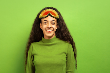 Image showing African-american young woman\'s portrait in ski mask on green background