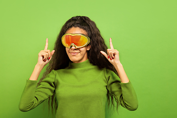 Image showing African-american young woman\'s portrait in ski mask on green background