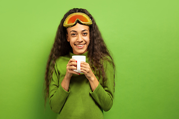 Image showing African-american young woman\'s portrait in ski mask on green background