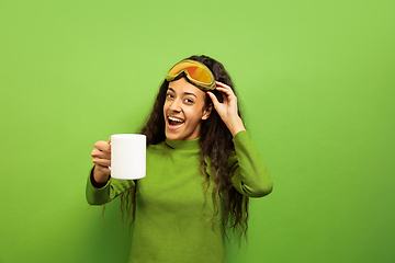 Image showing African-american young woman\'s portrait in ski mask on green background