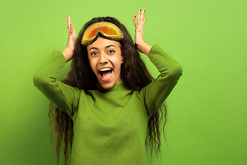 Image showing African-american young woman\'s portrait in ski mask on green background