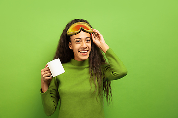 Image showing African-american young woman\'s portrait in ski mask on green background