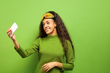 Image showing African-american young woman\'s portrait in ski mask on green background