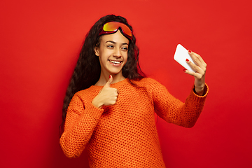 Image showing African-american young woman\'s portrait in ski mask on red background