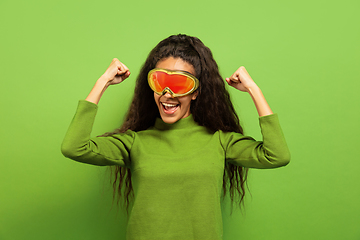 Image showing African-american young woman\'s portrait in ski mask on green background