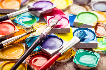 Image showing Set of watercolor paints and paintbrushes for painting closeup. 