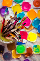 Image showing Set of watercolor paints and paintbrushes for painting closeup. 