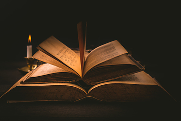 Image showing Old antique books with candle in vintage style on black background