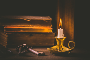 Image showing Pile of old antique books with candle in vintage style on black background