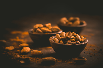 Image showing Organic cocoa beans in small bowls on brown background