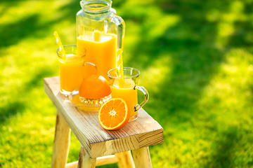 Image showing Two glasses of tasty freshly squeezed orange juice on garden stool