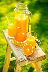 Image showing Two glasses of tasty freshly squeezed orange juice on garden stool