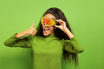 Image showing African-american young woman\'s portrait in ski mask on green background