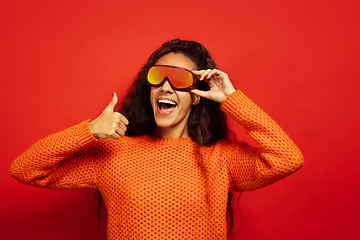 Image showing African-american young woman\'s portrait in ski mask on red background