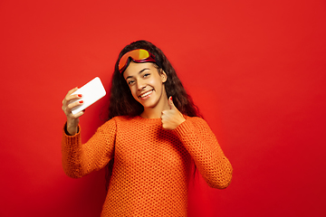 Image showing African-american young woman\'s portrait in ski mask on red background