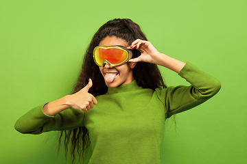 Image showing African-american young woman\'s portrait in ski mask on green background