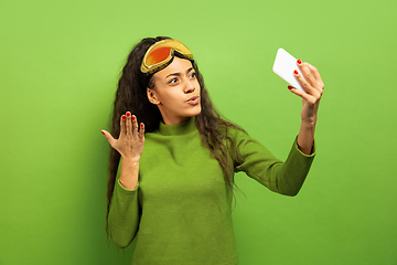 Image showing African-american young woman\'s portrait in ski mask on green background