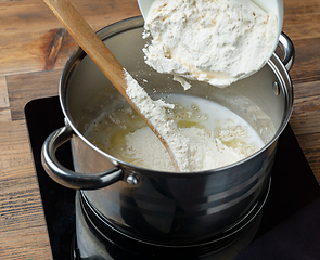 Image showing flour is poured into a pot with hot water and butter