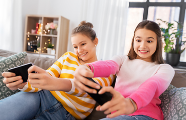 Image showing girls and playing game on smartphones at home